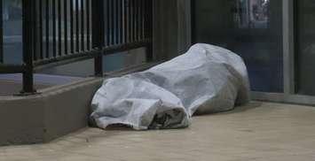 A homeless person sleeping outside of a building. (File photo by Miranda Chant, Blackburn Media)