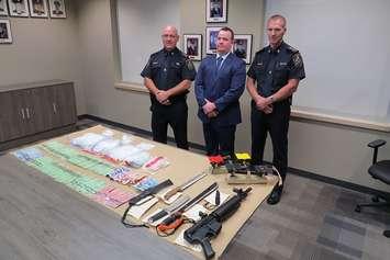 St. Thomas police Inspector Hank Zehr, Detective Constable Frank Boyes, and Chief Chris Herridge display the drugs, weapons, and cash seized in the city's largest drug bust to date, September 25, 2018. (Photo by Miranda Chant, Blackburn News)