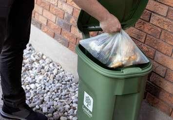 A person depositing kitchen scraps into their green bin. Photo provided by the City of London.