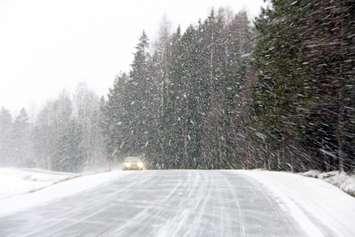 Car driving on a rural road in a snowstorm. © Can Stock Photo / Taina