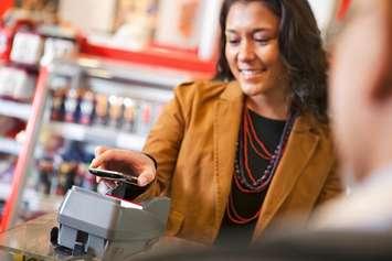 A woman pays for an item at a business. File photo courtesy of © Can Stock Photo / Leaf