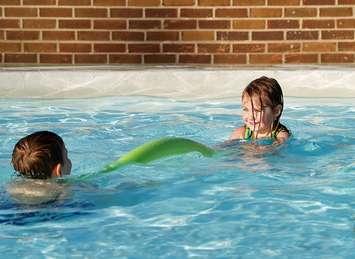 Kids playing in a backyard swimming pool file photo courtesy of © Can Stock Photo / sparkia