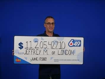 Londoner Jeff McNally stands with his novelty cheque for over $11.2 million. Photo courtesy of the OLG. 