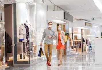 A couple wearing face masks walk through a mall. File photo courtesy of  © Can Stock Photo / dolgachov