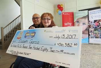 Elizabeth Garcia and her husband Tony hold the winning cheque for the Dream Lottery 50/50 draw, July 13, 2017. (Photo by Miranda Chant, Blackburn News.)