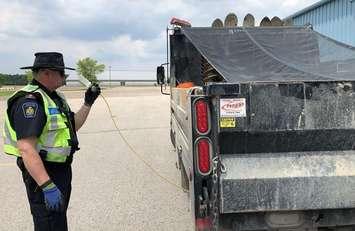 A Ministry of Finance representative conducts a fuel test on a commercial vehicle during a safety blitz in Middlesex Centre, June 19, 2019. Photo courtesy of OPP.