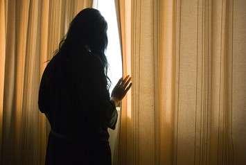 A woman looks out a window. File photo courtesy of © Can Stock Photo / corolanty