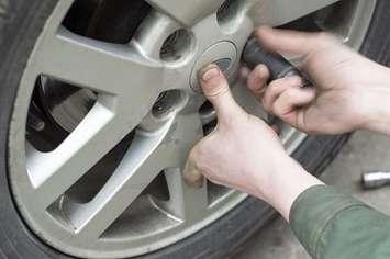 A lug nut is removed from a vehicle's tire. File photo courtesy of © Can Stock Photo / vectorass