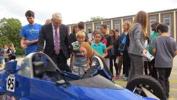 Waterloo-based racer Amy Castell shows Federal Transport Minister Marc Garneau, Grade 4 student Valeria Campos, and Grade 5 student Malachy Elliott her race car at Arthur Ford PS in London, September 14, 2016. (Photo by Miranda Chant, Blackburn News.)