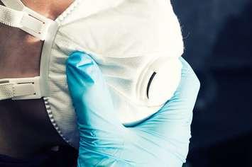 Person wearing a surgical mask and gloves. File photo courtesy of © Can Stock Photo / pabkov