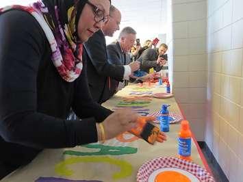 Diversity, Inclusion, and Anti-Oppression Advisory Committee Chair Rifat Hussain, Mayor Matt Brown, and Fanshawe College President Peter Devlin add their hand prints to a #HandsAgainstRacism banner, March 21, 2017. (Photo by Miranda Chant, Blackburn News.)