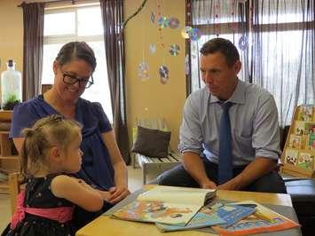 Ontario PC Leader Patrick Brown reads a story to 3-year-old Zoe Wilson and her mother Tanya at the St. Thomas Early Learning Centre, July 11, 2017. (Photo by Miranda Chant, Blackburn News.)